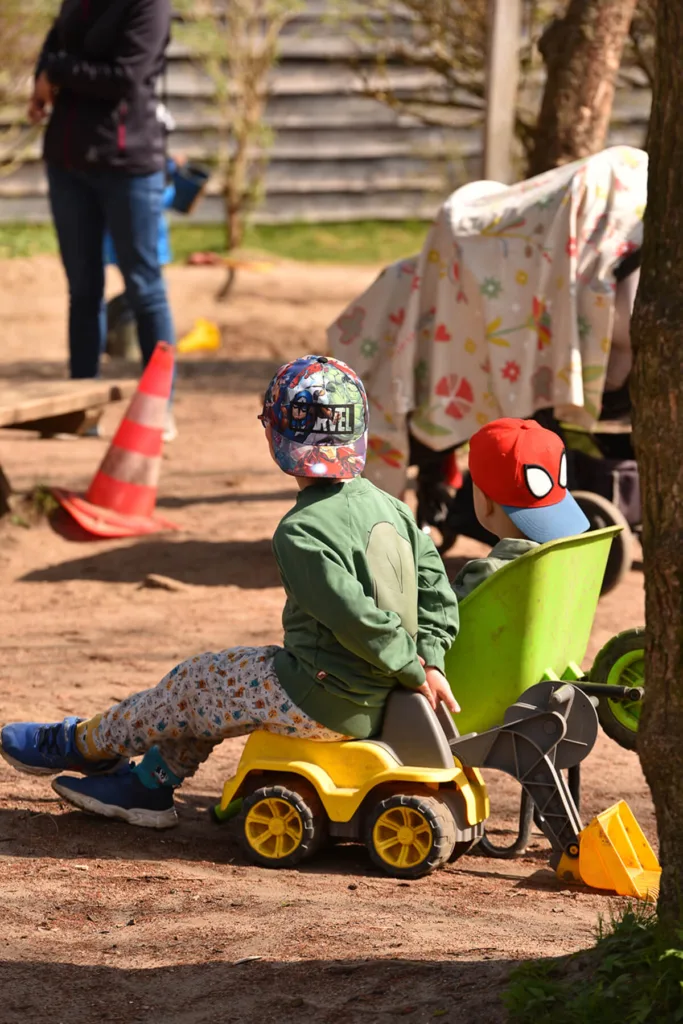 Kinder spielen mit Bobbycars auf dem Spielplatz der Kinderkreisel-Kita Pinguinegruppe.