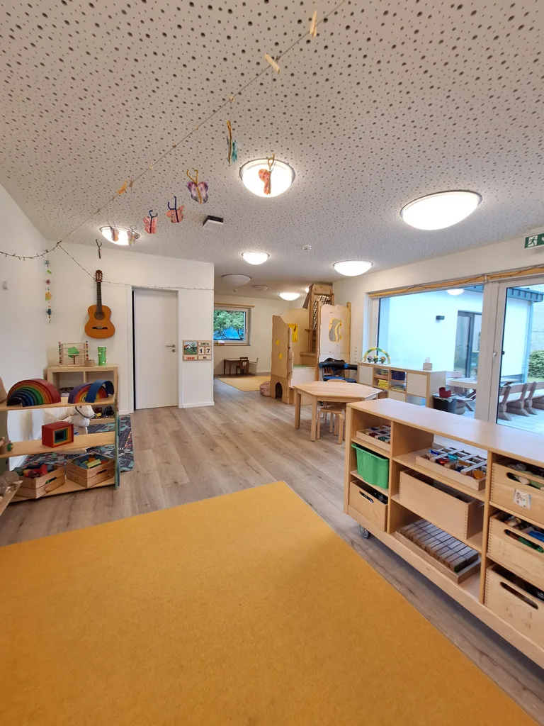 Bauecke der Kinderkreisel Kita mit selbstgebastelten Schmetterlingsgirlanden, Spielregalen und Kletterburg