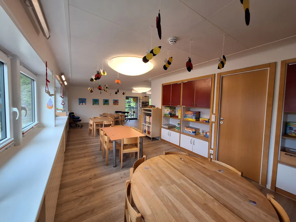 Esszimmer-Innenraum der Kinderkreisel-Kita Drachengruppe mit Kindertischen zum Essen, Spielen und Zeichnen.