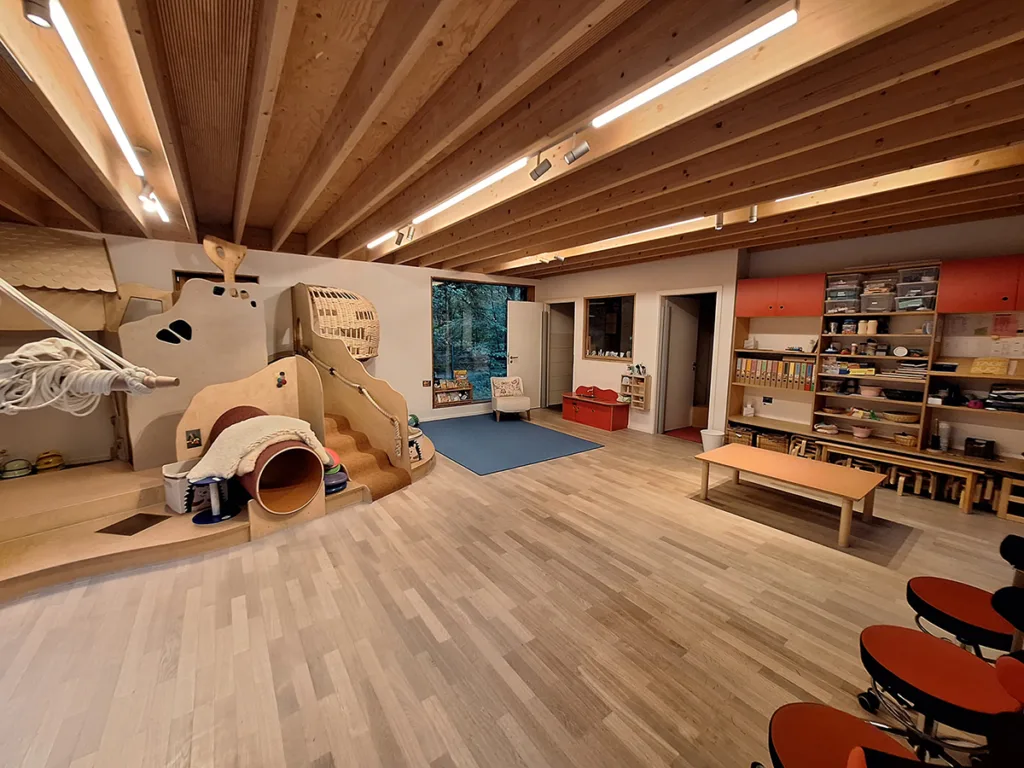 Gruppenraum der Kinderkreisel-Kita Igelgruppe mit Kletterburg, viel Spielfläche und zahlreichen Aufbewahrungsmöglichkeiten wie Regalen für Spielzeug, Bastelmaterial und Brettspiele.