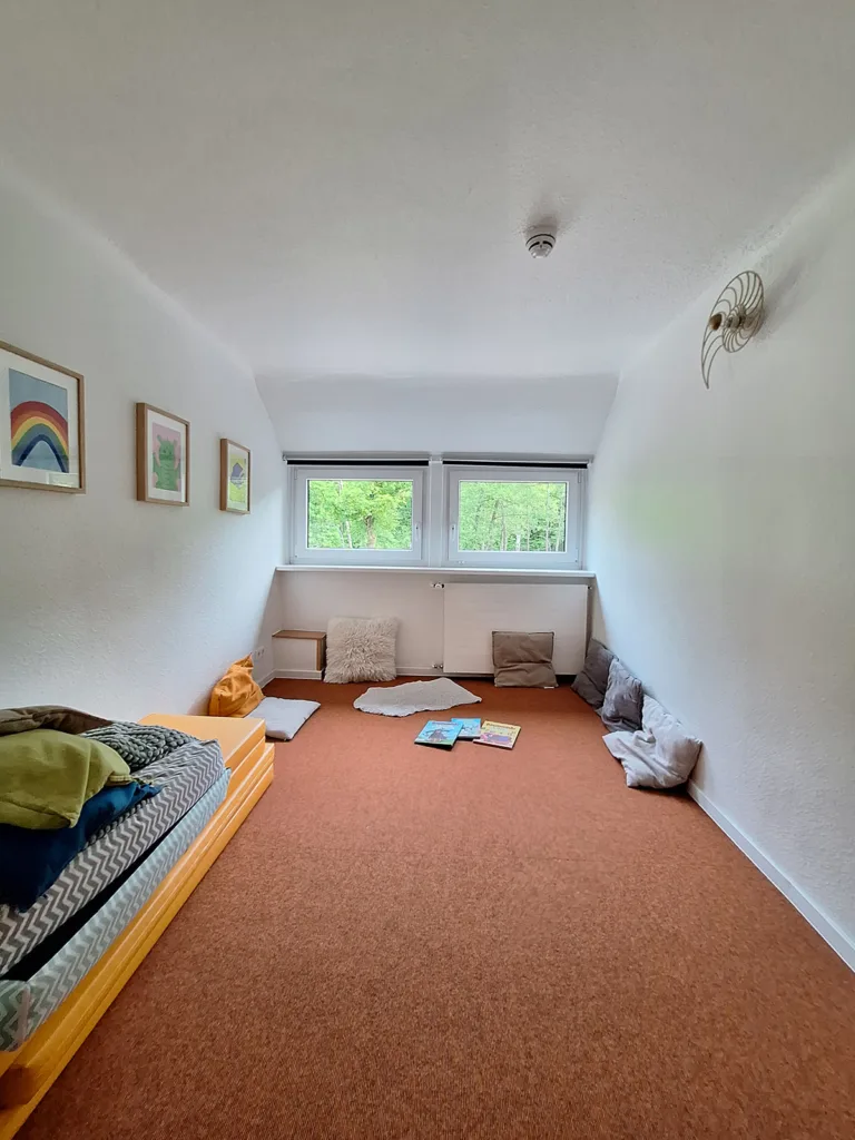 Ruhiger Innenraum der Kinderkreisel-Kita Drachengruppe mit Matten und Kissen zum Anlehnen und Lesen.