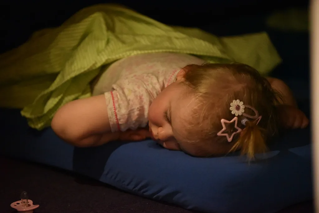 Kleinkind schläft ruhig auf einer Matratze im Schlafraum der Kinderkreisel-Kita.“